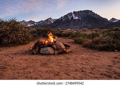 desert campfire in stone fire pit at base of mountains under sunset sky - Powered by Shutterstock