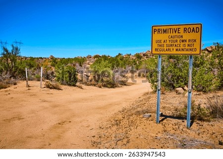 Desert Caution Sign on Primitive Road with Power Lines and Brush Eye Level View