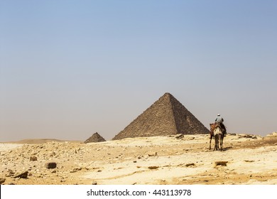 desert egypt pyramids. Beduin on a camel on the background of the desert and the pyramids of Menkaure, Giza, Egypt