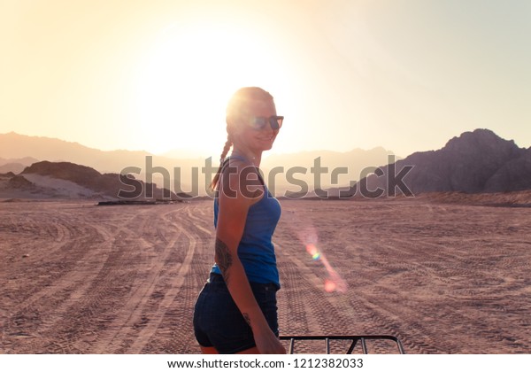 Desert in Egypt. Sharm el Sheikh. Sand and Sand\
Borkhan. Rock and sunset. Quad Cycle Travel. Excursion with\
people.Girl in blue t-shirt and\
shorts.
