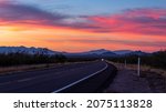 A desert highway with a colorful orange, red, purple and blue sky. A beautiful Southwestern sunset along US 80 looking west between Bisbee and Tombstone, in Cochise County, Arizona, USA.