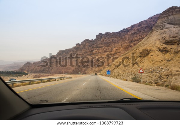 Desert highway and mountains through car window\
not far from Dead sea in\
Jordan