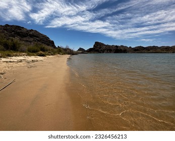 A desert landscape of beautiful shoreline along the Colorado River in the Topock Gorge in Arizona. The ripples in the water reflect the activity of the boaters and jet skiers.