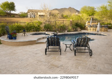 A desert landscaped backyard featuring a travertine pool deck and outdoor kitchen.
				