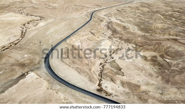 Desert road - Aerial image of a new two lane\
road surrounded by dry desert\
landscape