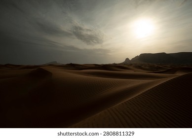 Desert Sand Dunes at Sunset with Dramatic Sky and Mountain Silhouette