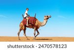 Desert, Teenager rider mounted brown Camel travel around desert. Decorated saddle. Man upon wildlife animal with hump. Safari transportation.