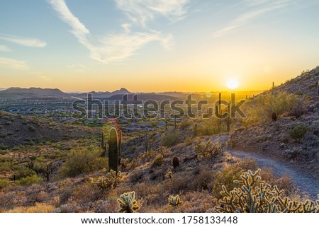 A desert trail on a mountain leading to a sunset over a valley in Phoenix, Arizona.
