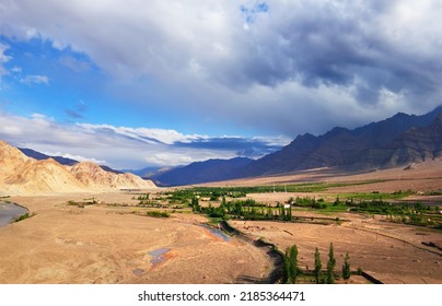 Desert valley, few huts and trees, barren mountains and dramatic blue sky. Beautiful scenic view from Stagna Gompa (Stakna monastery), Leh district, Ladakh, Himalayas, Jammu Kashmir, Northern India
