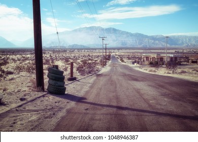 Deserted abandoned empty road in San Felipe, Mexico, South California, mountain peak in distance with blue sunny sky with few white clouds, dirty wide road and several empty houses, no people or cars - Powered by Shutterstock