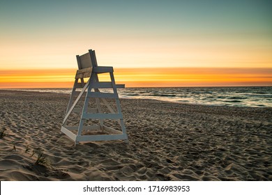 A deserted beach with a  colorful dawn sky and empty lifeguard stand on Long Beach Island, NJ