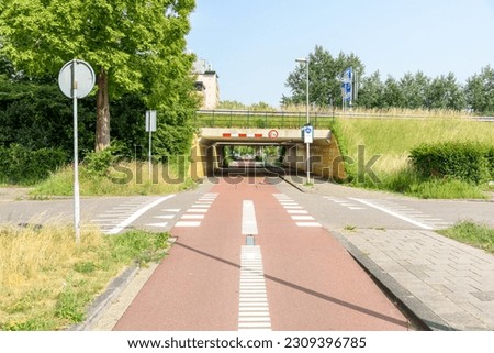 Deserted bicycle path passing under  a motorway on a sunny summer day