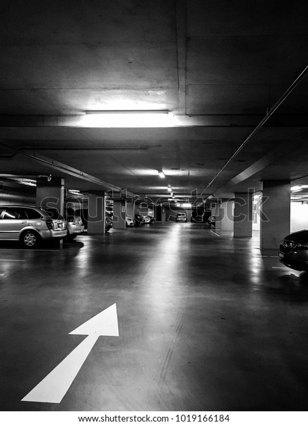 Deserted car park with large, white arrow in the
foreground in black and
white.