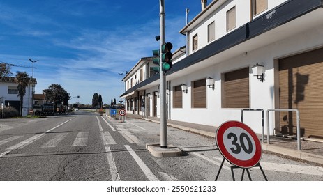 A deserted European street with traffic signals and a speed limit sign, illustrating urban planning and road safety challenges - Powered by Shutterstock