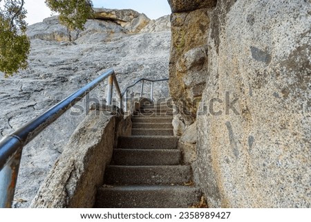 Deserted narrow stairway with metal handrails leading up a rocky mountain peak
