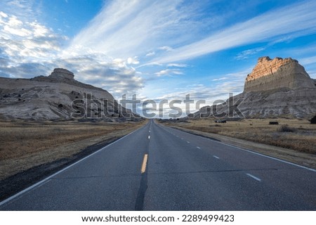 Deserted road through the Old Oregon Trail at sunset in Scotts Bluff National Monument Nebraska with blue sky and clouds.