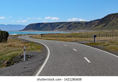 A deserted road winds towards the bay at Cape Palliser, North, Island, New Zealand - Powered by Shutterstock