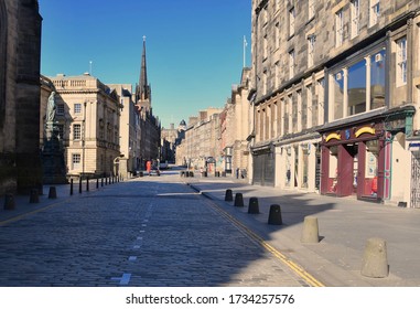 Deserted Royal Mile, as the UK lockdown continues and people stay at home except for daily exercise.  Lone female jogger runs past empty stores and pubs. Edinburgh City, Scotland UK. may 2020