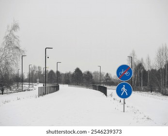 Deserted snow-covered pedestrian path in a city park. Road signs - Powered by Shutterstock