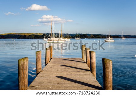 Deserted Wooden Jetty on Connecticut River at Sunset. Some Anchored Sailing Boats are visible in Background.