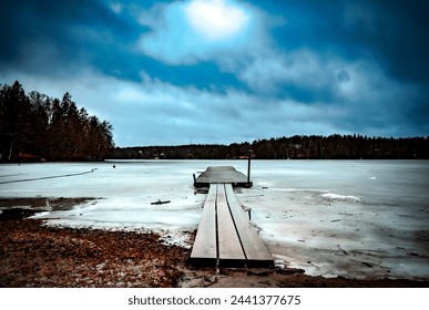 A deserted wooden pier stretches into a frozen lake. - Powered by Shutterstock