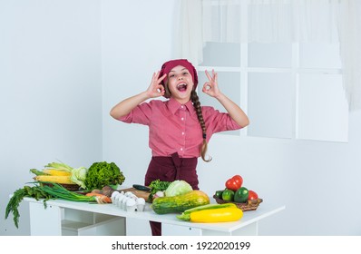 Deserve well. child show ok gesture. cook with vegetables at kitchen. natural useful food. health and dieting. happy childhood. happy teenage girl preparing meal. kid wear chef uniform.