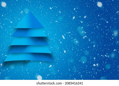 Design of blue christmas tree with paper texture and snowy background. Christmas concept for advertising.