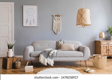 Design bohemian composition of living room interior with gray sofa, wooden cube, commode, beige macrame, rattan lamp ,plants, plaid, flowers and elegant accessories. Stylish home decor. Template.