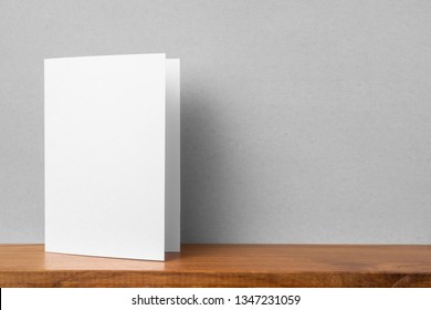 Design concept - front view of greeting card on bookshelf and grey wall for mockup, not 3D render - Shutterstock ID 1347231059