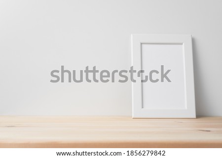 Design concept - front view of vertical white wood photo frame on wood floor whit white wall for mockup