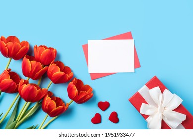 Design concept of Mother's day holiday greeting gift with red tulip bouquet and card on bright blue table background
