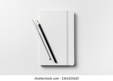 Design concept - top view of close white notebook with elastic band and 2 wooden pencil isolated on white background for mockup. real photo, not 3D render