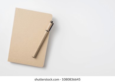 Design Concept - Top View Of Hardcover Kraft Notebook And Ballpoint Pen Isolated On White Background For Mockup