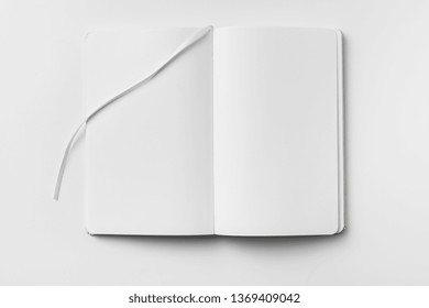 Design concept - top view of open white notebook with blank page and ribbon bookmark isolated on white background for mockup.
