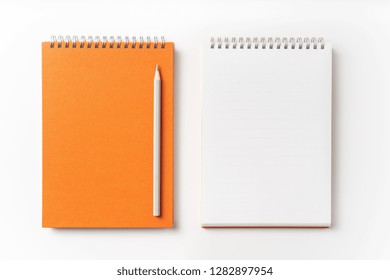 Design Concept - Top View Of Orange Spiral Notebook, White Page And Pencil Isolated On Background For Mockup