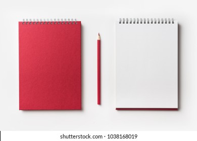Концепция дизайна - Вид сверху красного спирального ноутбука и коллекции цветных карандашей, изолированных на белом фоне для макета