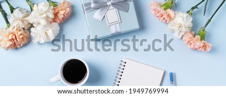 Design concpet of Mother's Day greeting with carnation flower, holiday gift idea and notebook diary on mother's desk background.