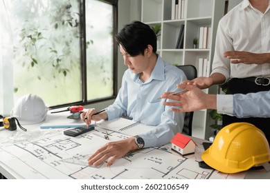 Design Development and Collaboration. An architect analyzing project designs while discussing with teammates in a modern office.
