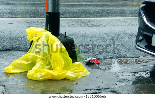 Design an example of a people outline of a\
raincoat  lying on the ground after a car accident The concept of\
danger on the road in the rainy\
season