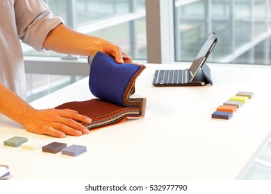 Design - Hands Looking Through Color Fabric Swatches On Desk With Colored Tiles