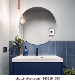 Designed Bathroom With Stylish Blue Cabinet, Blue Wall Tiles And Big Round Mirror