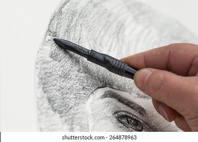 Designer with Charcoal drawing a face