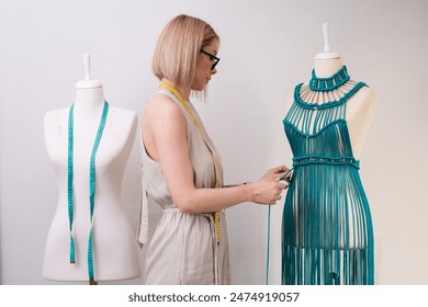 Designer creates unique green macrame dress on dummy in sewing atelier blonde woman ties knot on unfinished garment made of threads in dressmaking workshop - Powered by Shutterstock