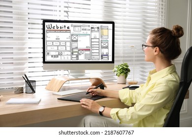 Designer creating website on computer at wooden table - Shutterstock ID 2187607767