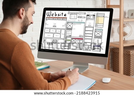 Designer creating website on computer at wooden table