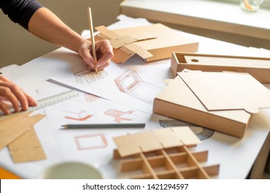 Designer draws a mockup for crafting cardboard box. Development of packaging design sketch. - Shutterstock ID 1421294597
