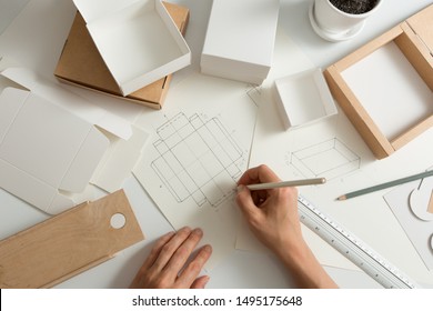 Designer draws a mockup for crafting eco cardboard box. Development a sketch of paper packaging.