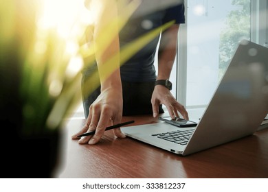 Designer Hand Working Laptop With Green Plant Foreground On Wooden Desk In Office