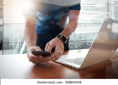  designer hand working and smart phone and laptop on wooden desk in office with london city background                               
