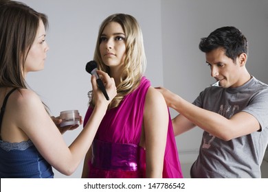 Designer And Makeup Artist Preparing Female Model For Photo Shoot